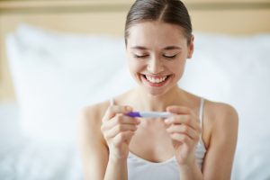 A woman smiling at a pregnancy test