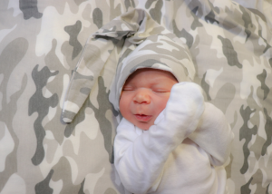 A newborn baby with a camo hat