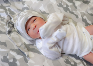 A newborn baby wearing a camo hat
