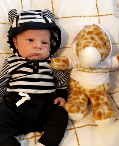 A baby next to a giraffe stuffed animal